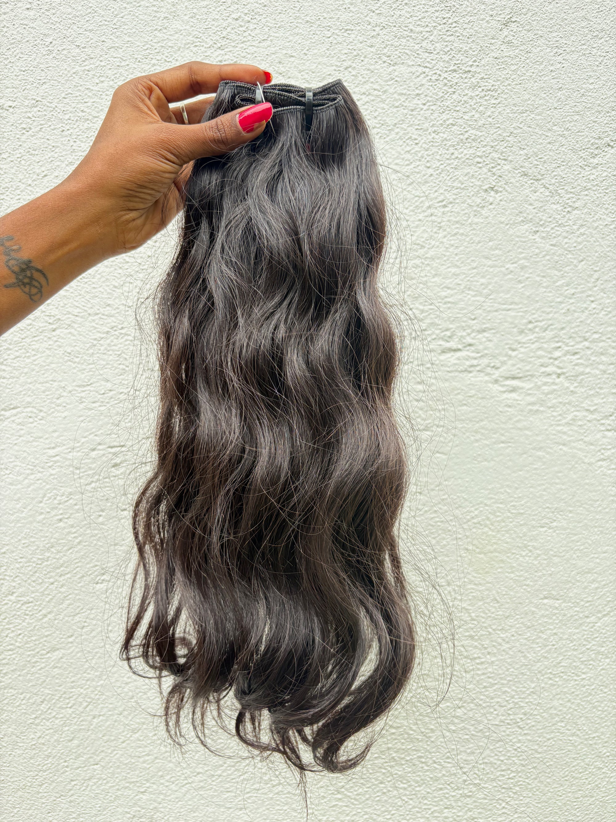 Hair extensions held by a hand against a light background