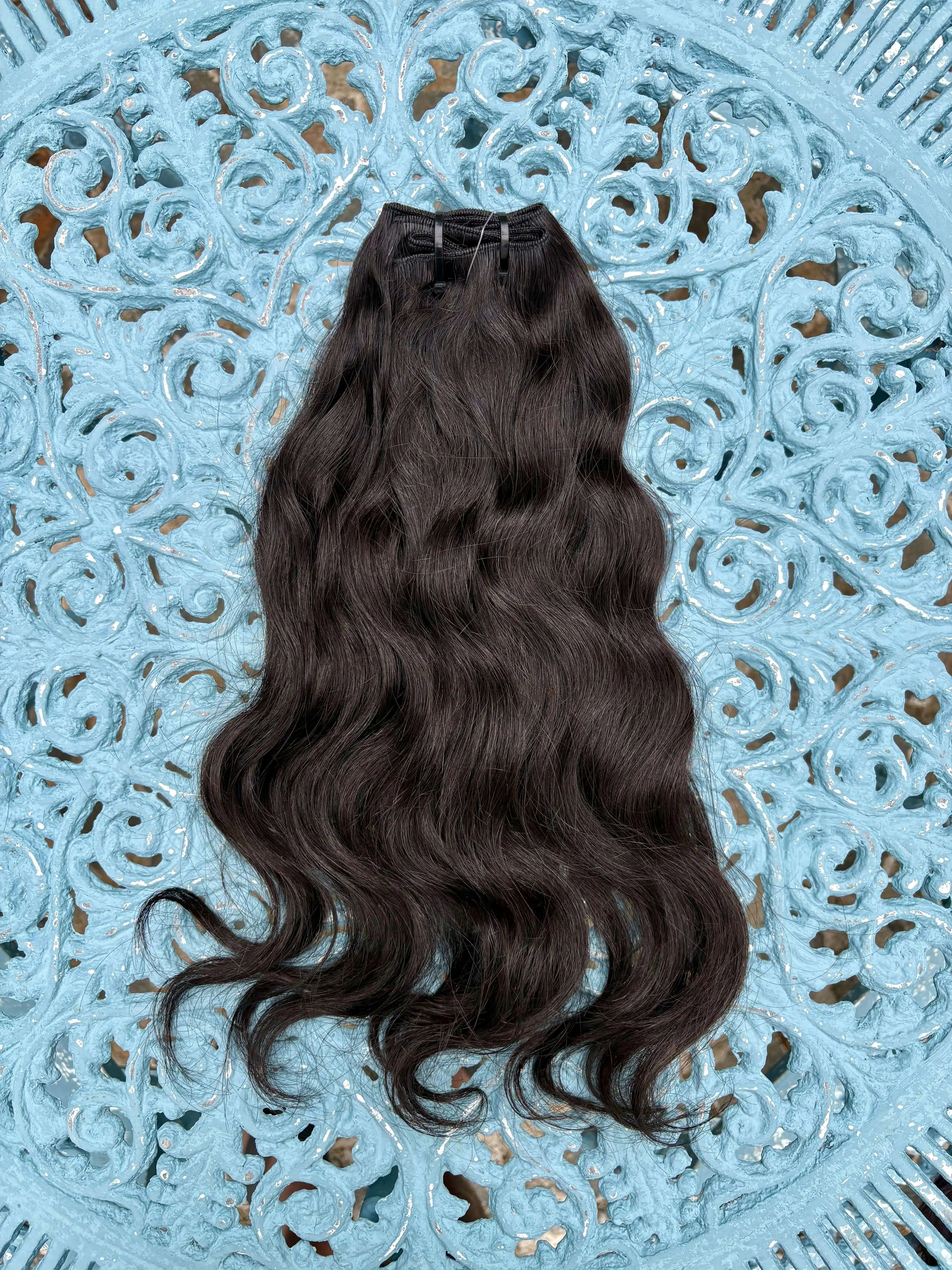 Raw Indian Hair Bundles on a decorative blue surface, showcasing its natural waves and rich texture.