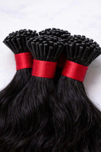 Detailed close-up of professional-grade keratin tips on wavy raw Indian hair extensions, optimized for micro-link and cold-fusion application.