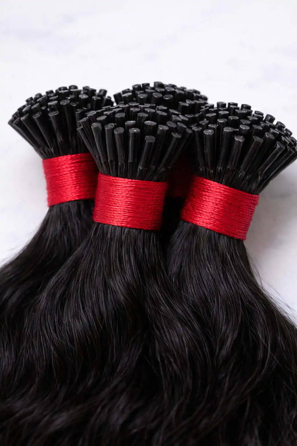 Detailed close-up of professional-grade keratin tips on wavy raw Indian hair extensions, optimized for micro-link and cold-fusion application.
