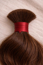 Close-up of natural brown wavy raw Indian bulk hair texture, highlighting the natural brown color, healthy luster and cuticle-aligned strength of single-donor, temple-sourced human hair.