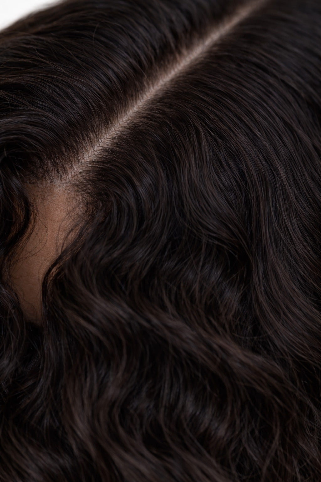 Close-up of authentic curly raw Indian hair showing defined natural ringlets and the healthy luster of unprocessed single-donor temple hair.