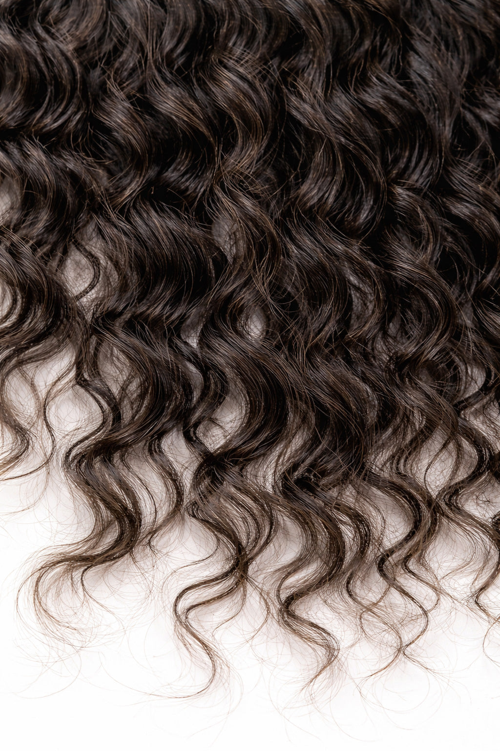 Macro shot of the natural curly pattern of raw Indian hair, highlighting the healthy luster and structural integrity of 100% single-donor, unprocessed temple hair.